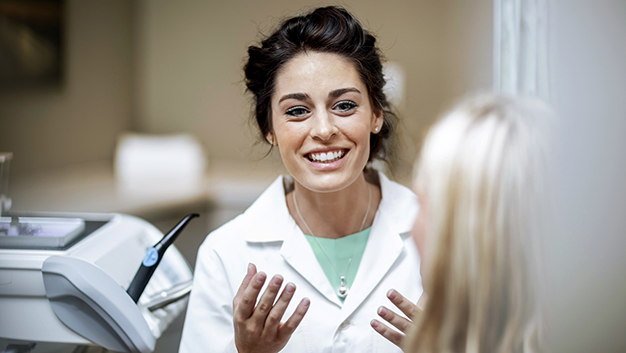 Dentist explaining procedure to patient sitting in dentists chair