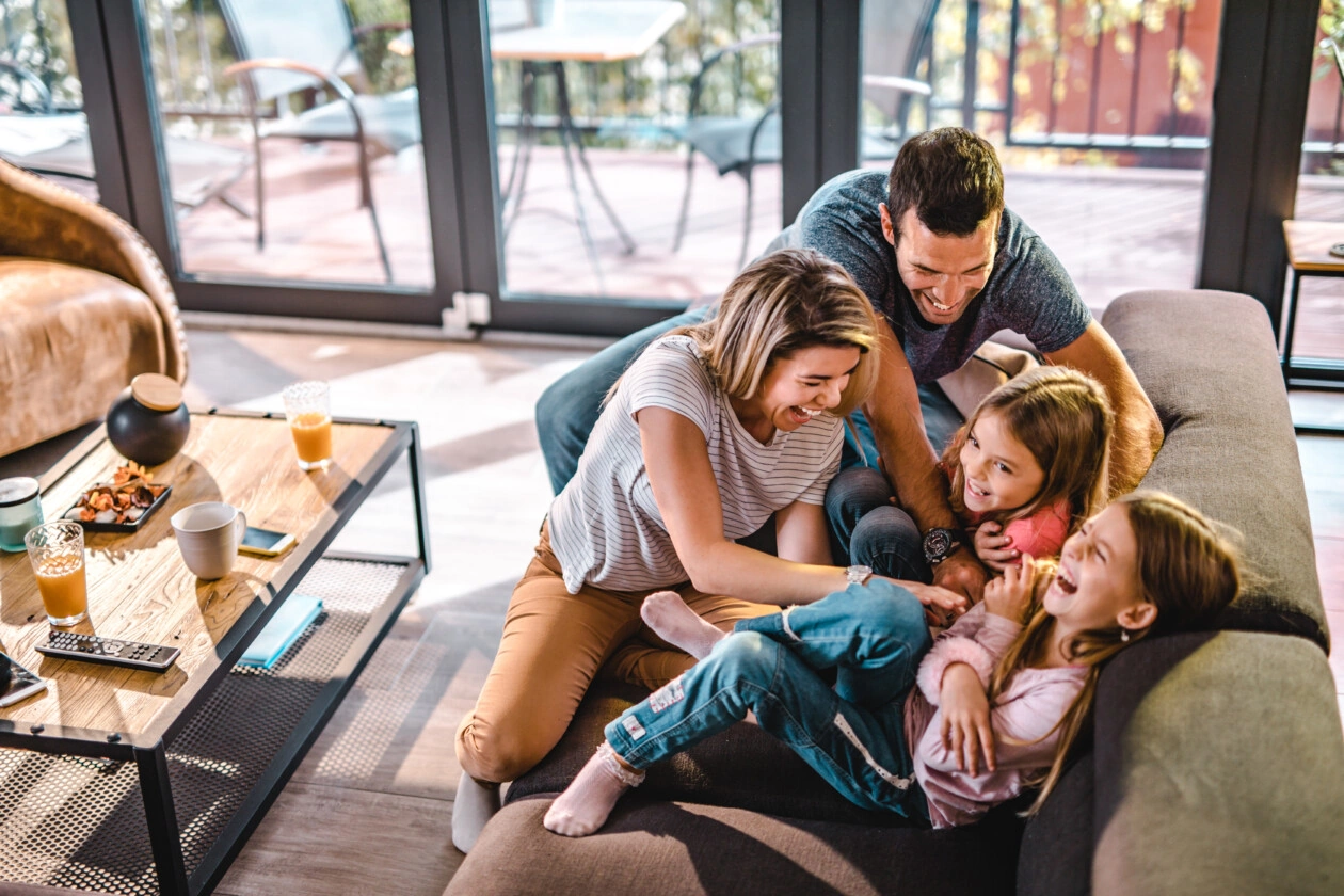 Above view of playful parents tickling their daughters at home.