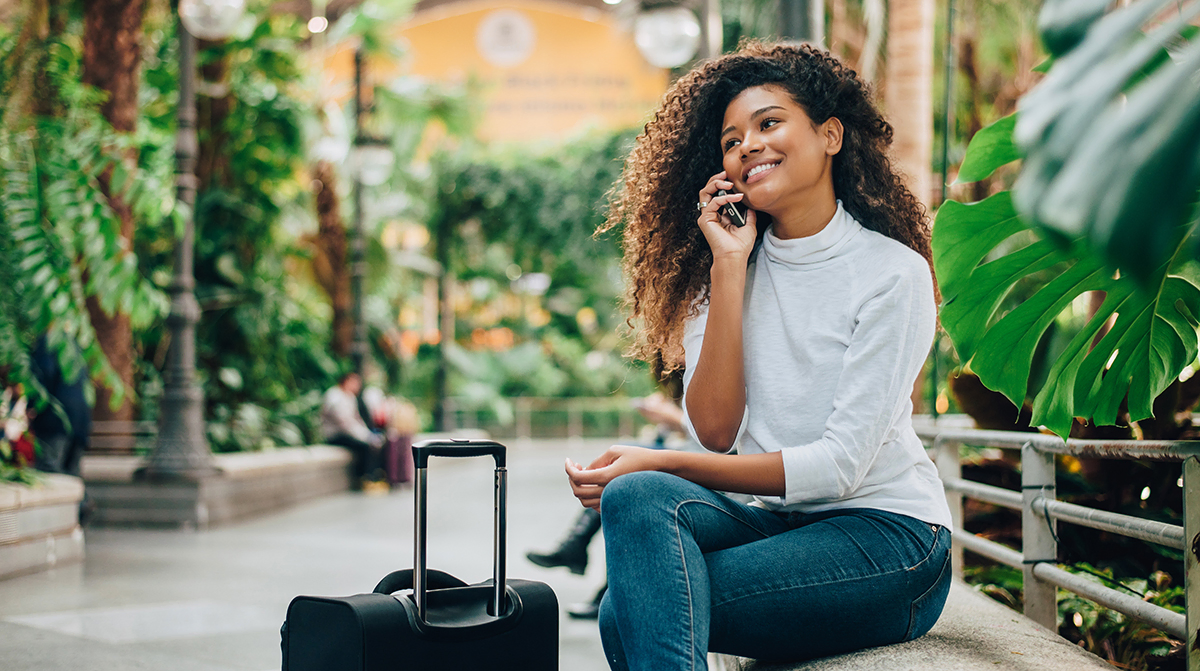 Young woman traveler with luggage talking on phone.