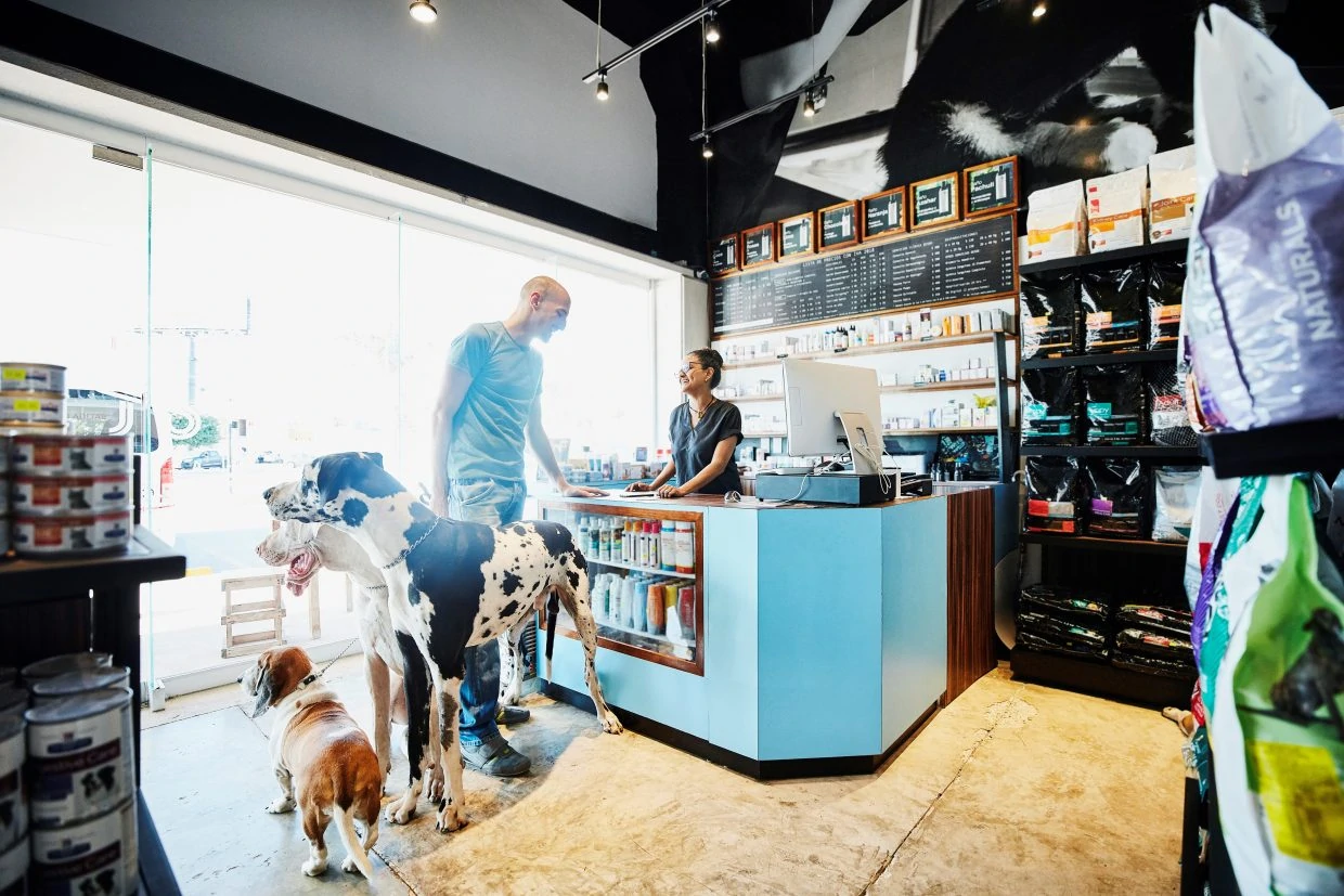 Smiling pet store owner helping customer with dogs check out